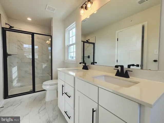 a bathroom with a double vanity sink toilet and shower