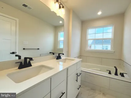 a bathroom with a granite countertop sink and a bathtub