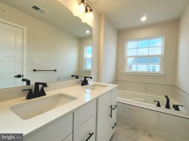 a bathroom with a granite countertop sink and a bathtub