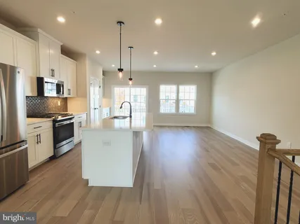 a kitchen with stainless steel appliances granite countertop a refrigerator a sink dishwasher a stove and white countertops with wooden floor