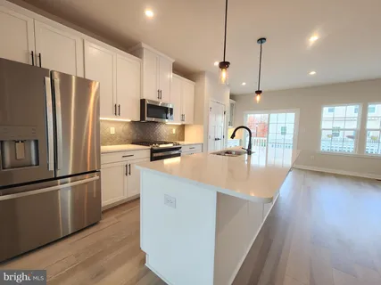 a kitchen with stainless steel appliances granite countertop a refrigerator a sink a stove and a wooden floors