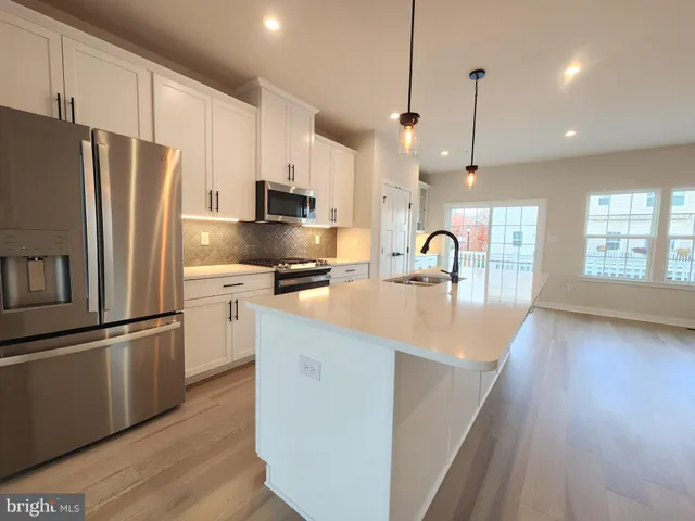 a kitchen with stainless steel appliances granite countertop a refrigerator a sink a stove and a wooden floors