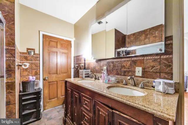a bathroom with a granite countertop double vanity sink and a mirror