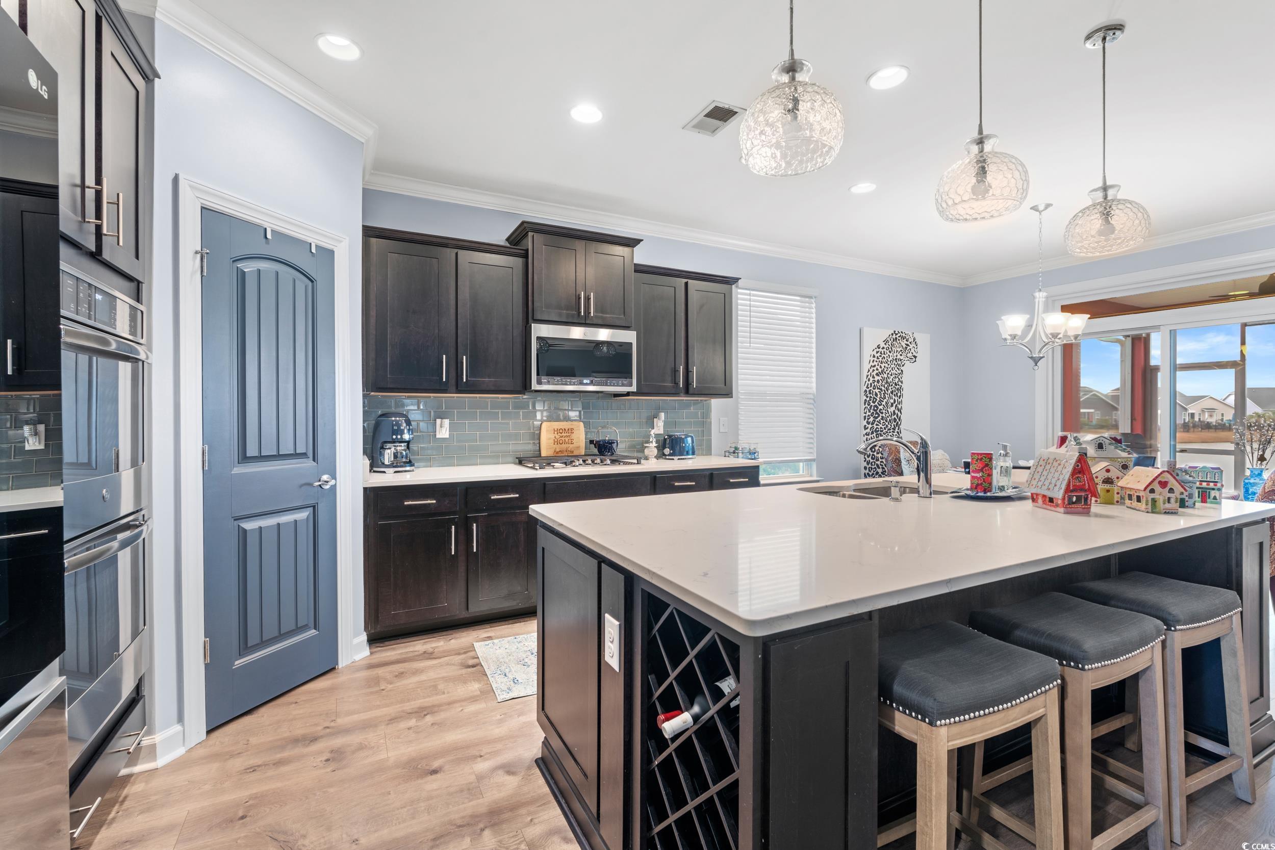 259 Switchgrass Loop Little River, SC 29566 - Photo 6 of 31 Gourmet Kitchen island featuring crown molding, a huge kitchen countertops, light wood finished floors, pendant lighting, and quartz countertops. Offering a double oven. Gas cooktop.
