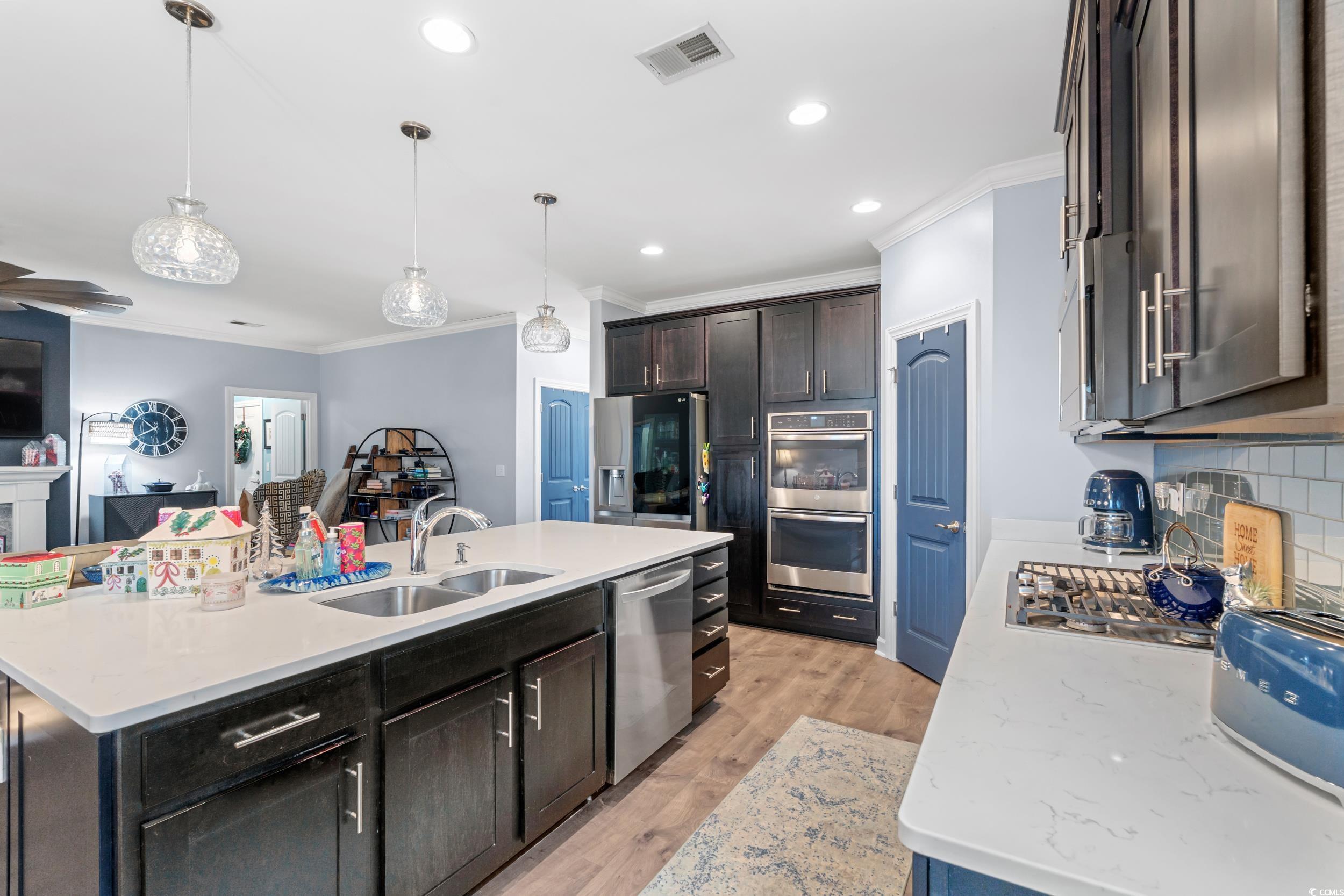 259 Switchgrass Loop Little River, SC 29566 - Photo 8 of 31 Kitchen with ornamental molding, decorative light fixtures, tasteful backsplash, light wood finished floors, and stainless steel appliances