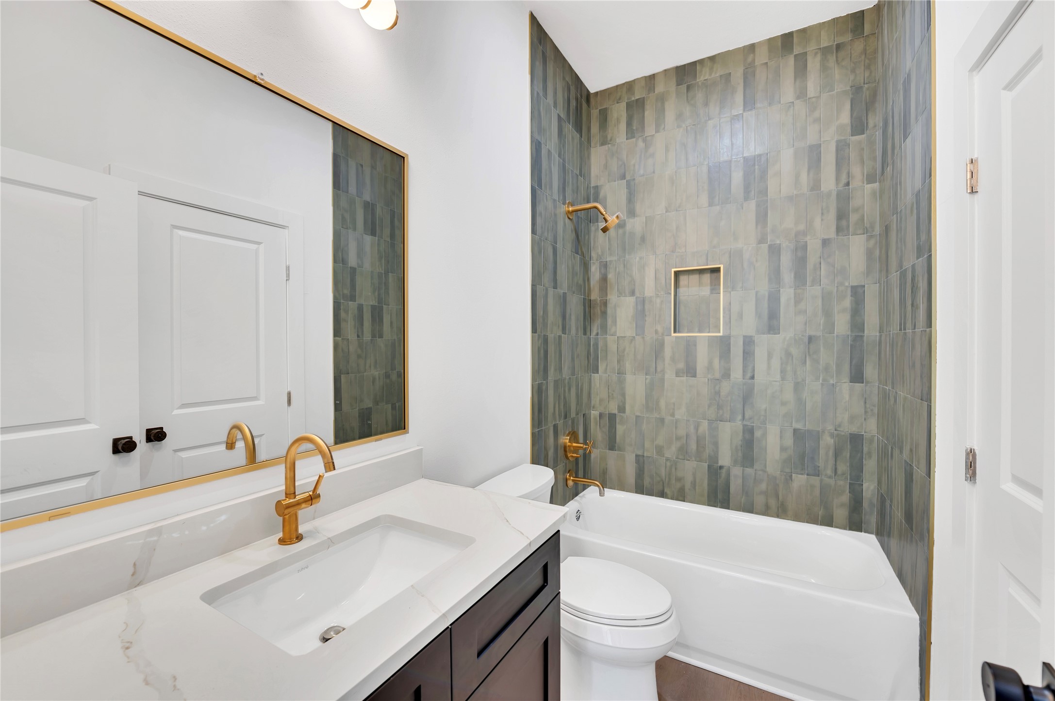 119 Kirby Road, Unit 5205 Seabrook, TX 77586 - Photo 13 of 46 Modern bathroom featuring elegant gold fixtures, a sleek vanity with a marble countertop, and a stylish tiled shower wall.