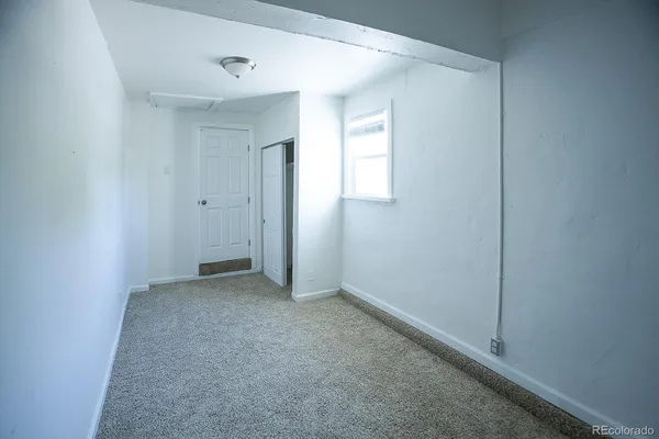a view of an empty room with closet and a window