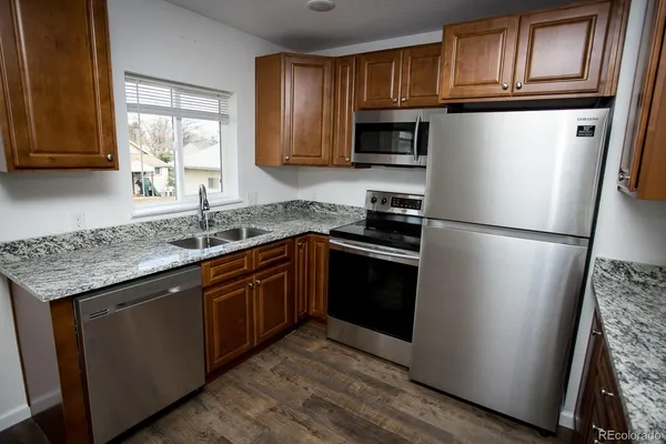 a kitchen with granite countertop wooden cabinets a refrigerator and a sink