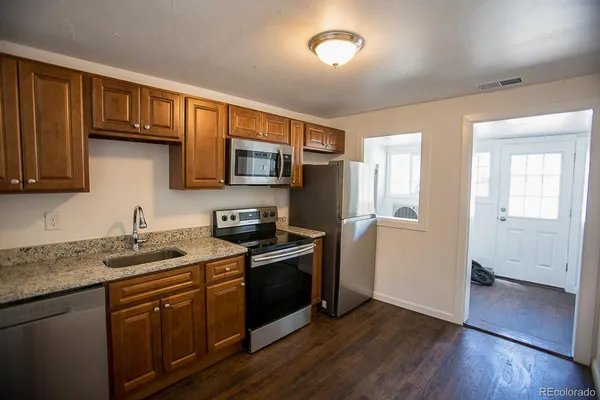 a kitchen with stainless steel appliances granite countertop wooden cabinets a stove top oven a sink and dishwasher