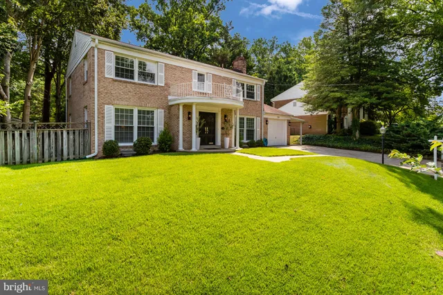 a view of a house with a yard and large trees