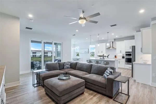 a living room with furniture kitchen area and a wooden floor