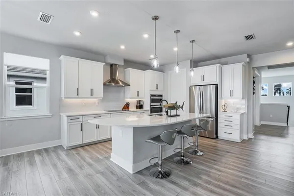 a large kitchen with stainless steel appliances kitchen island a large counter top and a wooden floors