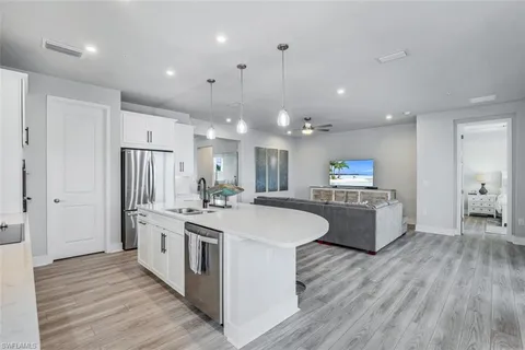 a kitchen with center island a sink dishwasher a dining table and chairs with wooden floor