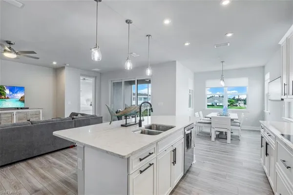 a view of a kitchen with kitchen island granite countertop wooden floor and a view of living room