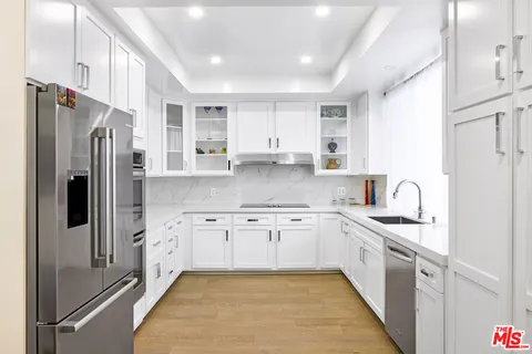 a kitchen with stainless steel appliances granite countertop a refrigerator a sink dishwasher a stove with white cabinets