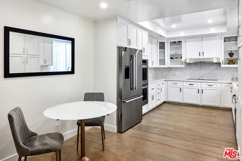 a kitchen with stainless steel appliances granite countertop a table chairs refrigerator and sink