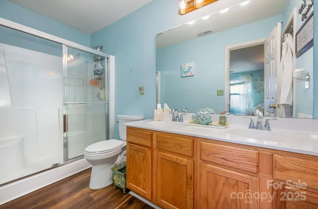 a bathroom with a granite countertop sink toilet a mirror and shower