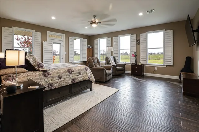 a bedroom with a large bed a large window with wooden floor