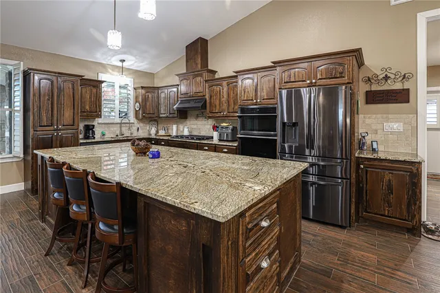 a kitchen with stainless steel appliances granite countertop a kitchen island a stove a refrigerator a sink and a refrigerator