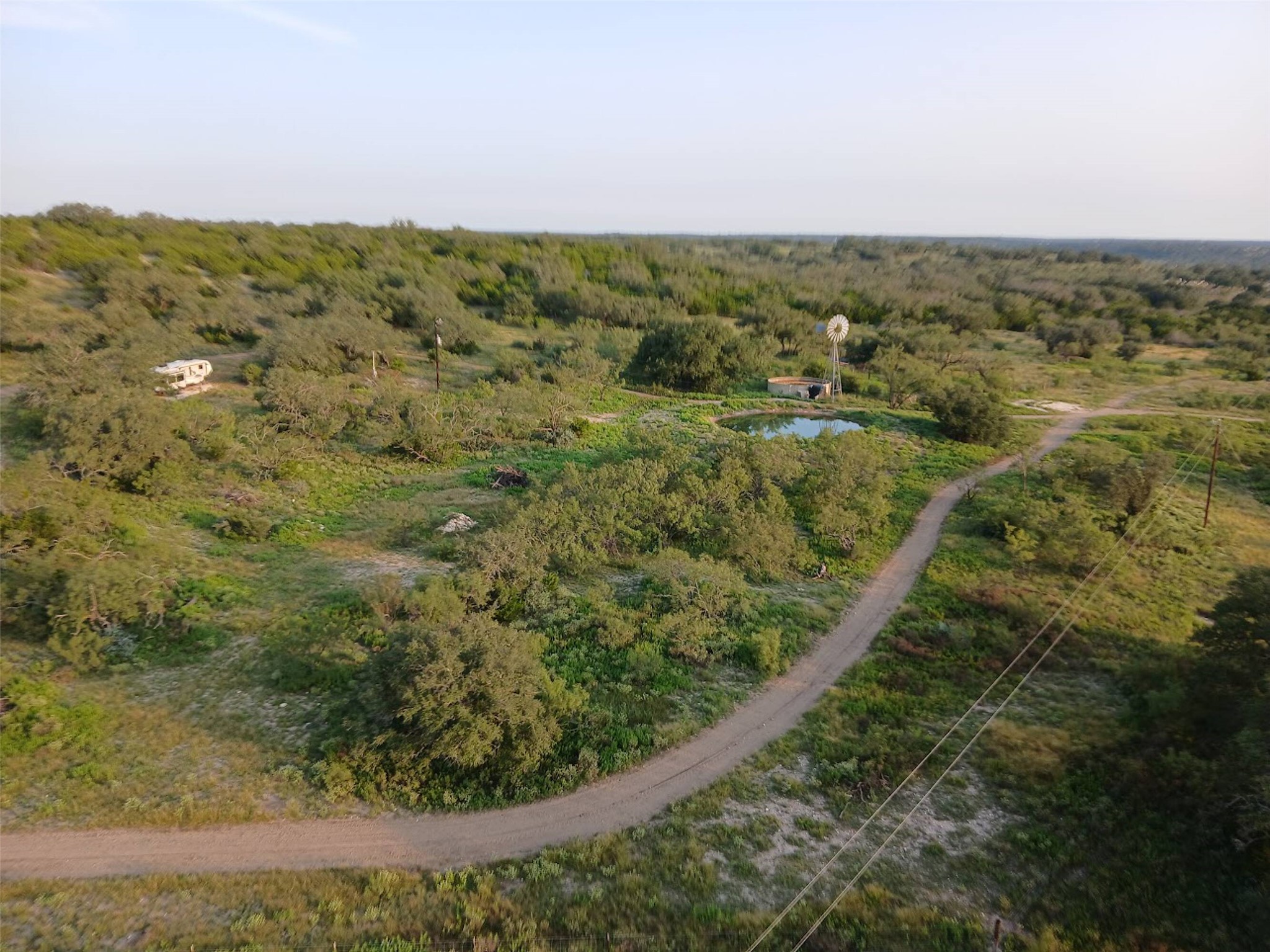 5 Dominion At Oak Ridge Junction, TX 76849 - Photo 26 of 34 Expansive undeveloped land featuring a private pond, a functional windmill, scattered trees, and a visible dirt road