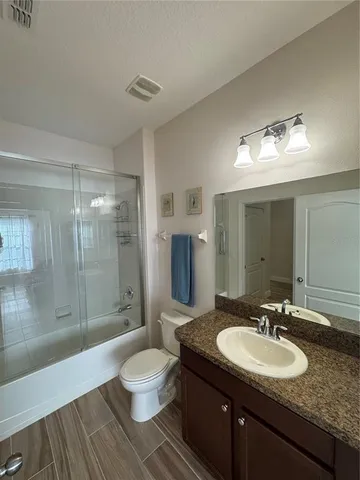 a bathroom with a granite countertop sink toilet a mirror and shower