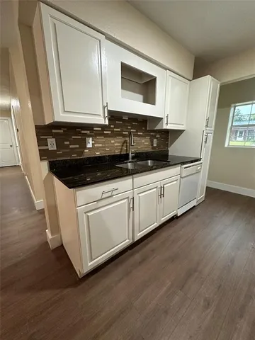 a kitchen with granite countertop white cabinets and a sink