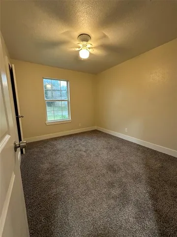 an empty room with a chandelier fan and windows