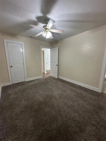 a view of an empty room with a chandelier fan