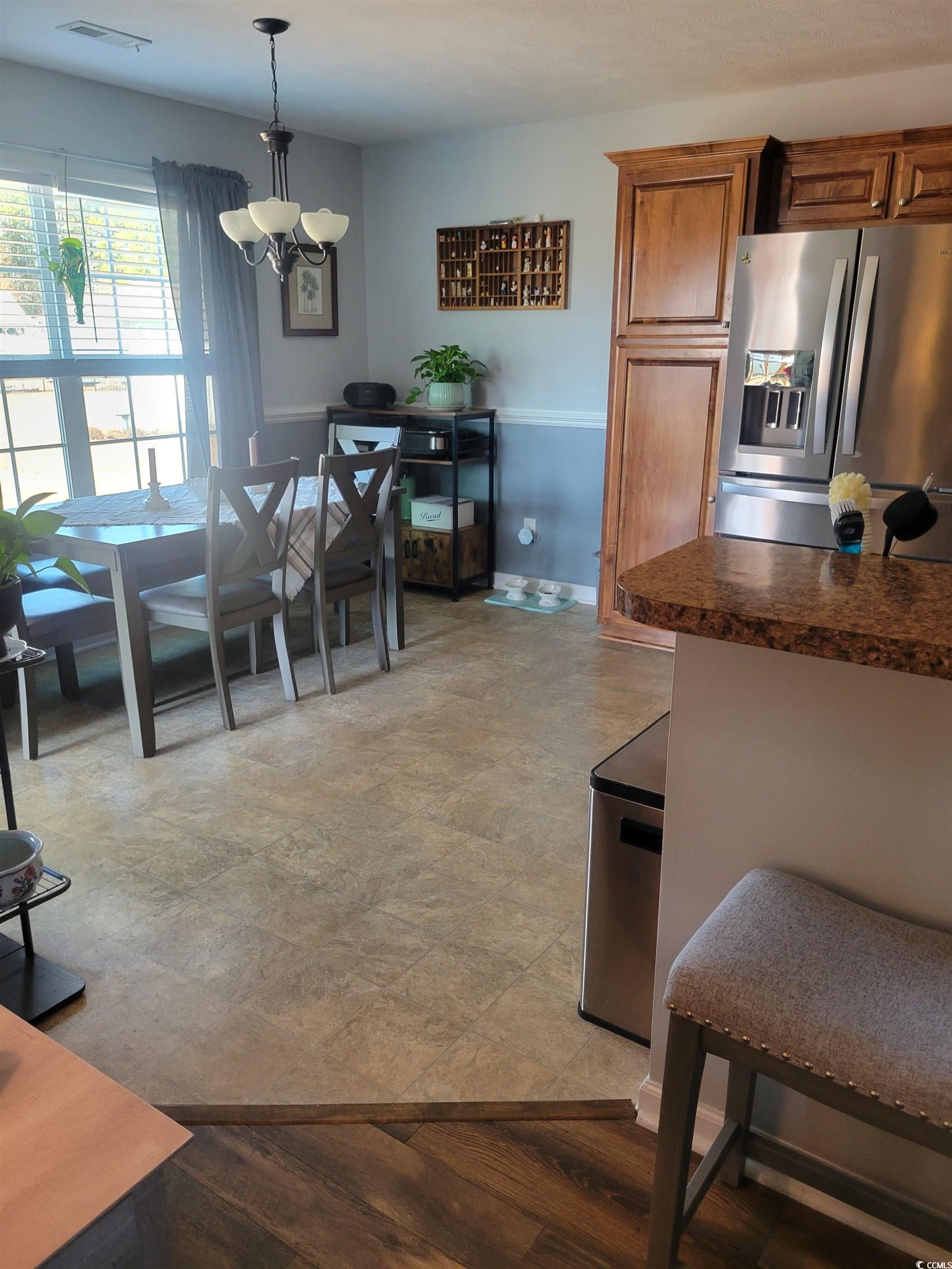 405 Beulah Circle Conway, SC 29527 - Photo 10 of 28 Kitchen featuring stainless steel refrigerator with ice dispenser, dark countertops, brown cabinets, pendant lighting, and light wood-style floors