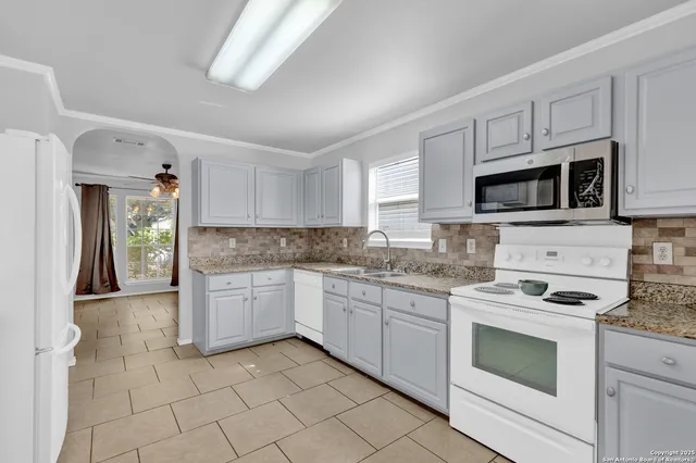 a kitchen with granite countertop white cabinets stainless steel appliances and a counter space