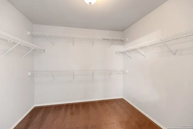 a view of an empty room with window and chandelier fan