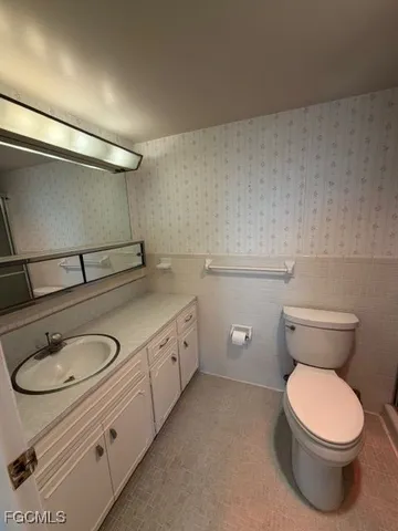 a bathroom with a granite countertop toilet and a sink