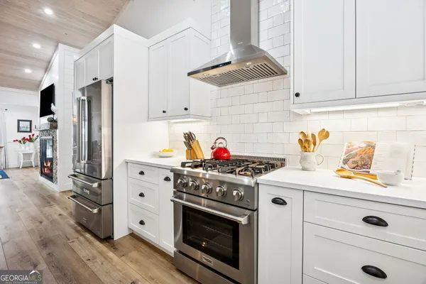 a open kitchen with stainless steel appliances granite countertop a refrigerator a sink dishwasher a dining table and chairs with wooden floor