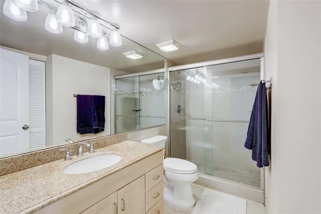 a bathroom with a granite countertop sink toilet and shower