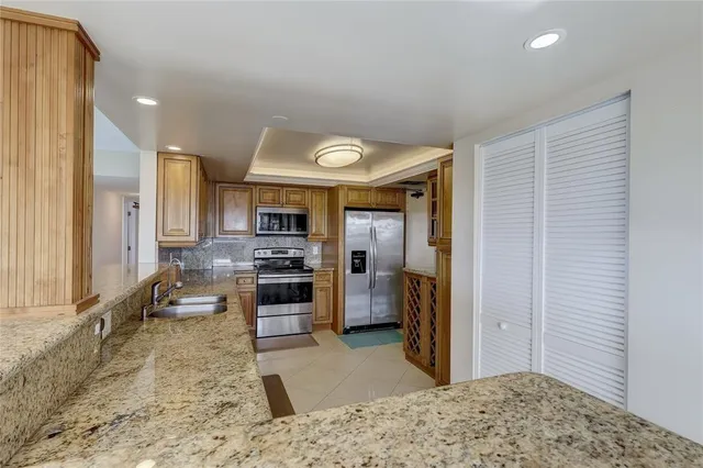 a living room with stainless steel appliances kitchen island granite countertop a refrigerator and a sink