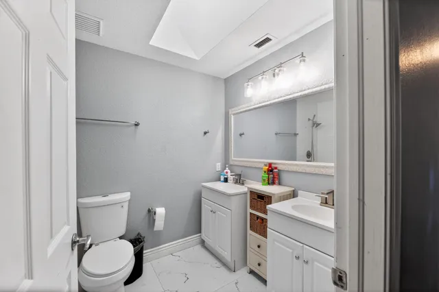 a bathroom with a toilet sink vanity and mirror