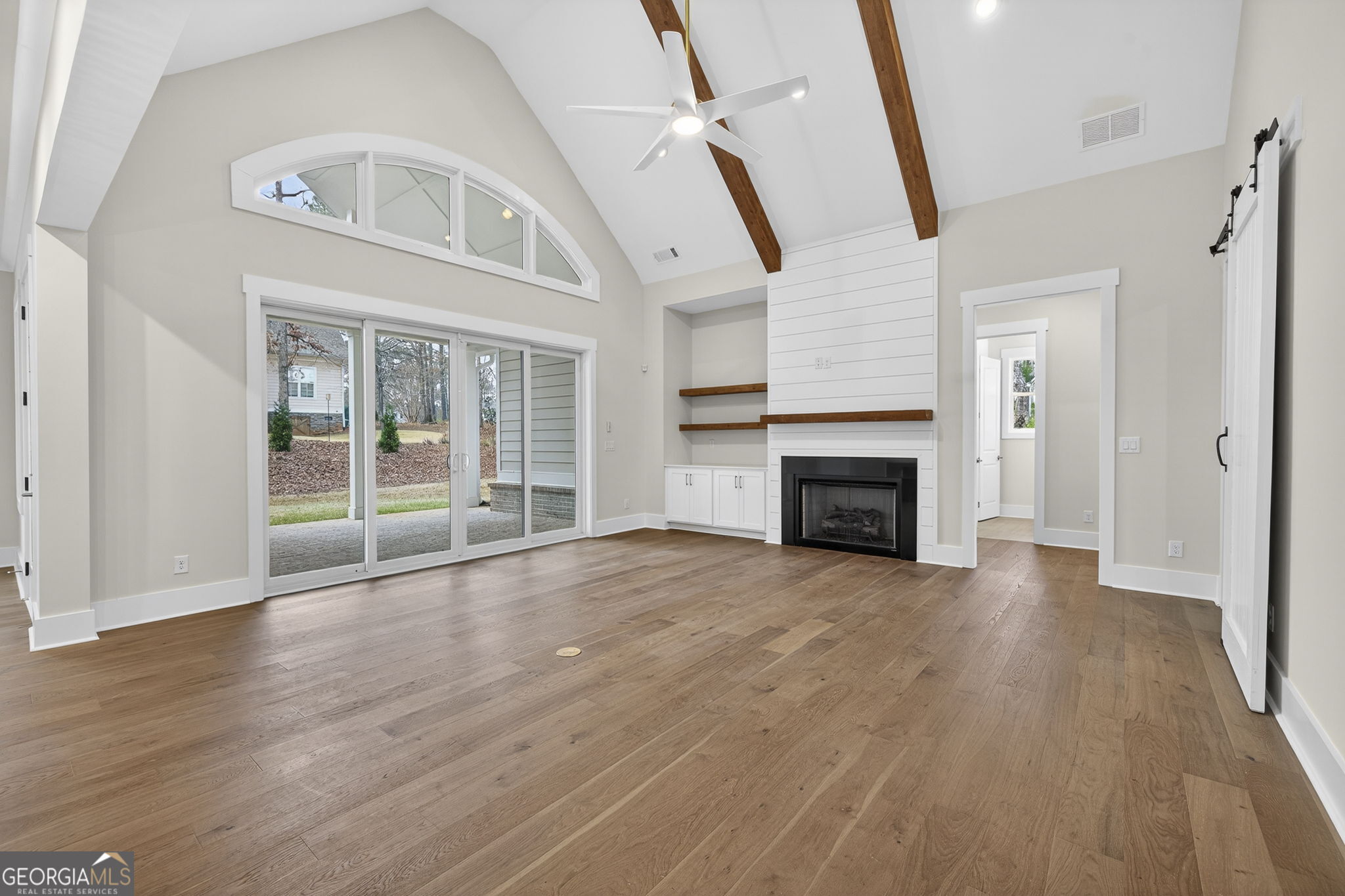 1020 Oak Valley Road Greensboro, GA 30642 - Photo 15 of 64 an empty room with wooden floor fireplace and windows