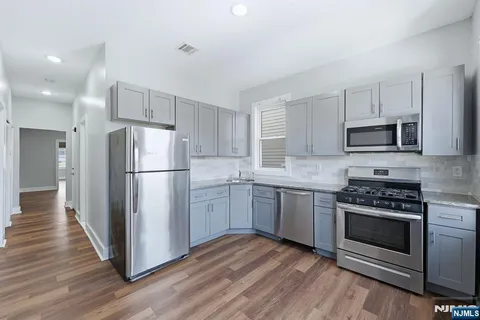 a kitchen with cabinets stainless steel appliances a sink and wooden floor