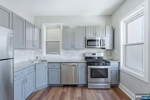 a kitchen with cabinets stainless steel appliances a sink and wooden floor