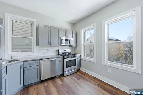 a kitchen with stainless steel appliances granite countertop hardwood floor sink and window
