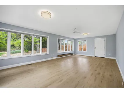 a view of an empty room with wooden floor and a window