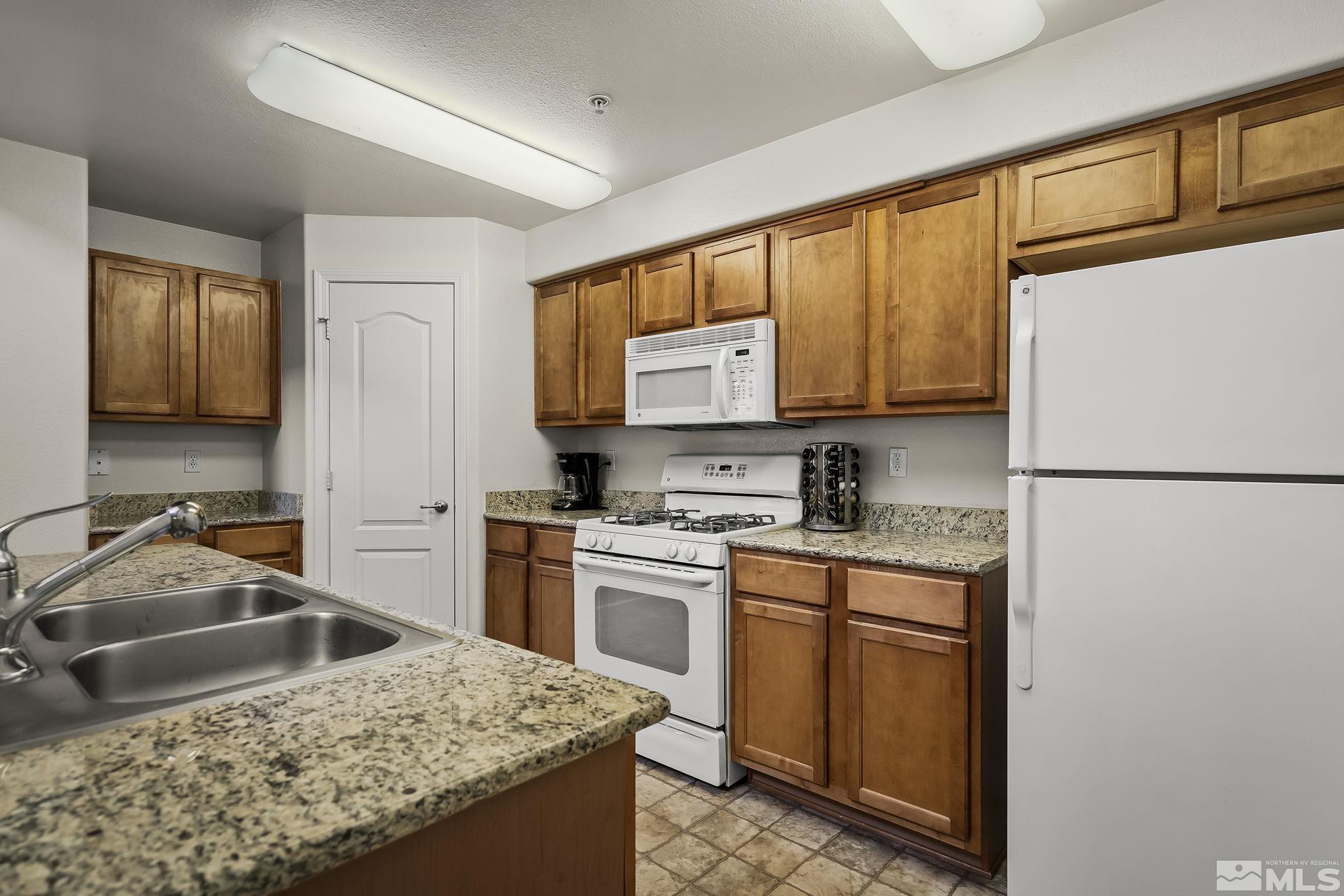 9050 Double R Boulevard, Unit 1622 Reno, NV 89511 - Photo 7 of 25 a kitchen with stainless steel appliances granite countertop a sink stove and refrigerator