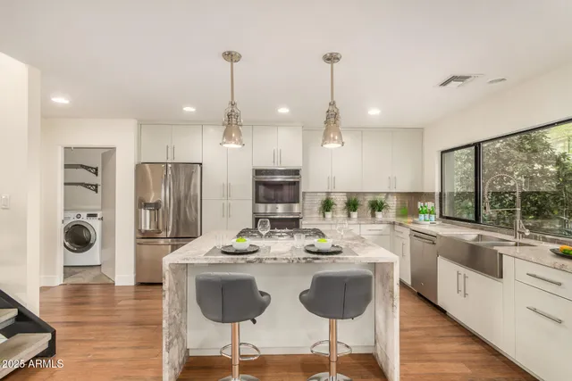 a kitchen with stainless steel appliances kitchen island granite countertop a stove a refrigerator a kitchen island a dining table and chairs