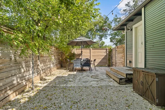 a view of a patio with table and chairs under an umbrella with large tree
