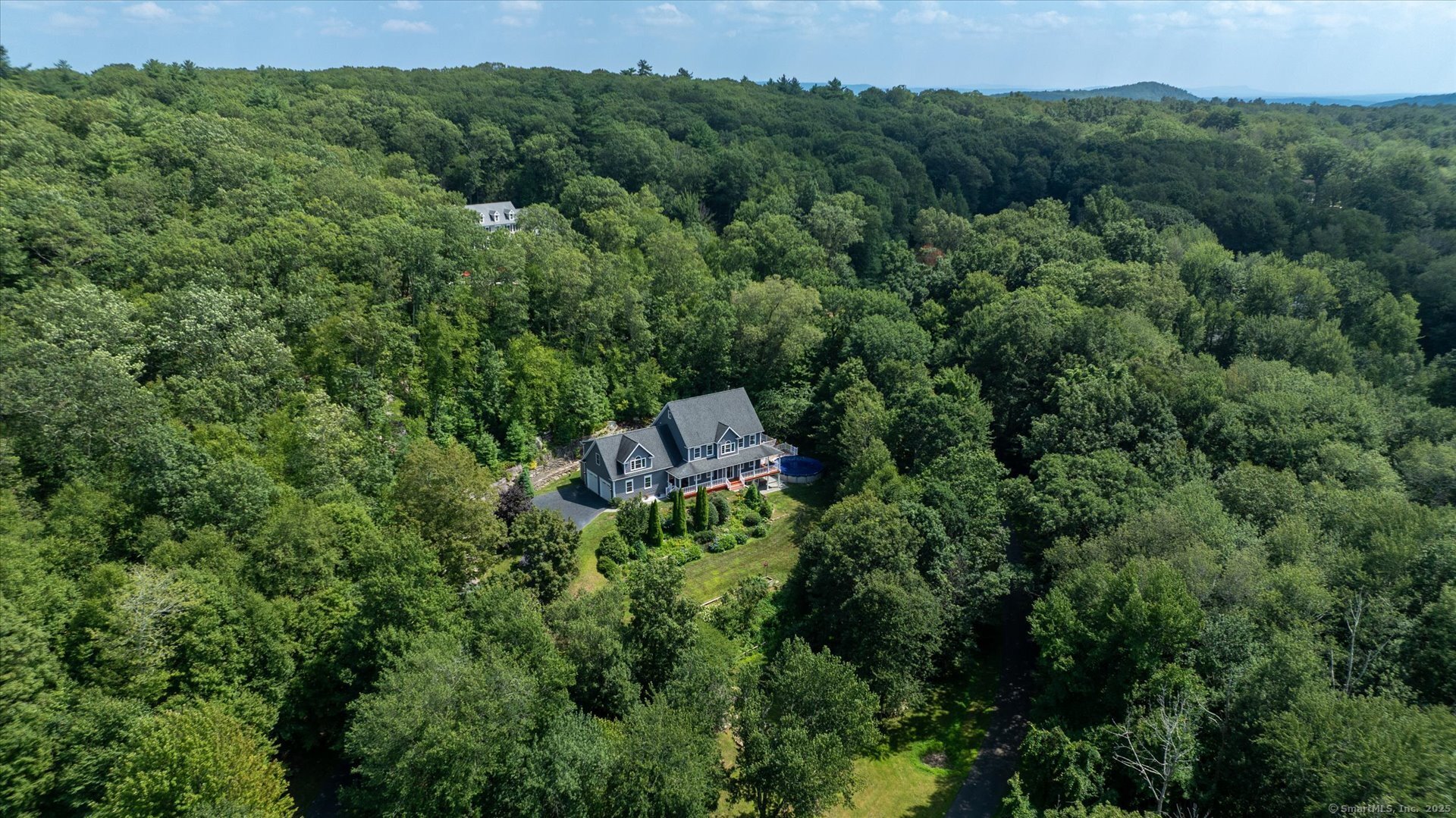 an aerial view of a house with a lush green forest