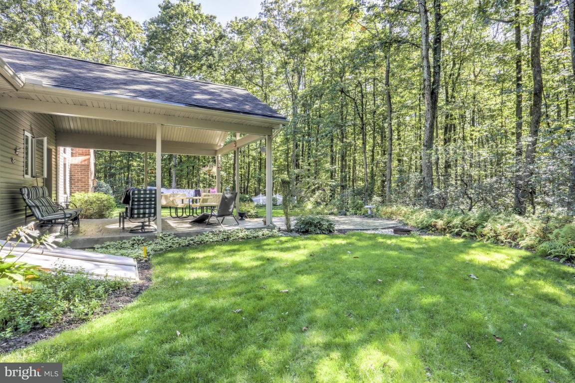 1136 Ranck Road New Holland, PA 17557 - Photo 30 of 37 a view of a patio with table and chairs under an umbrella with large trees