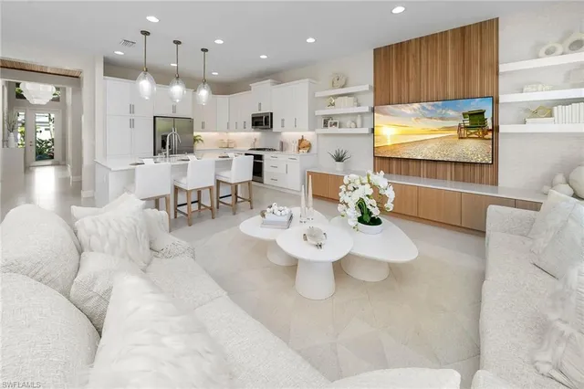 a living room with stainless steel appliances furniture a dining table and chairs