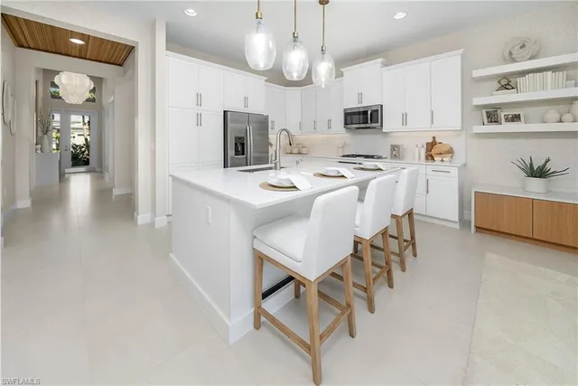 an open kitchen with kitchen island white cabinets and stainless steel appliances