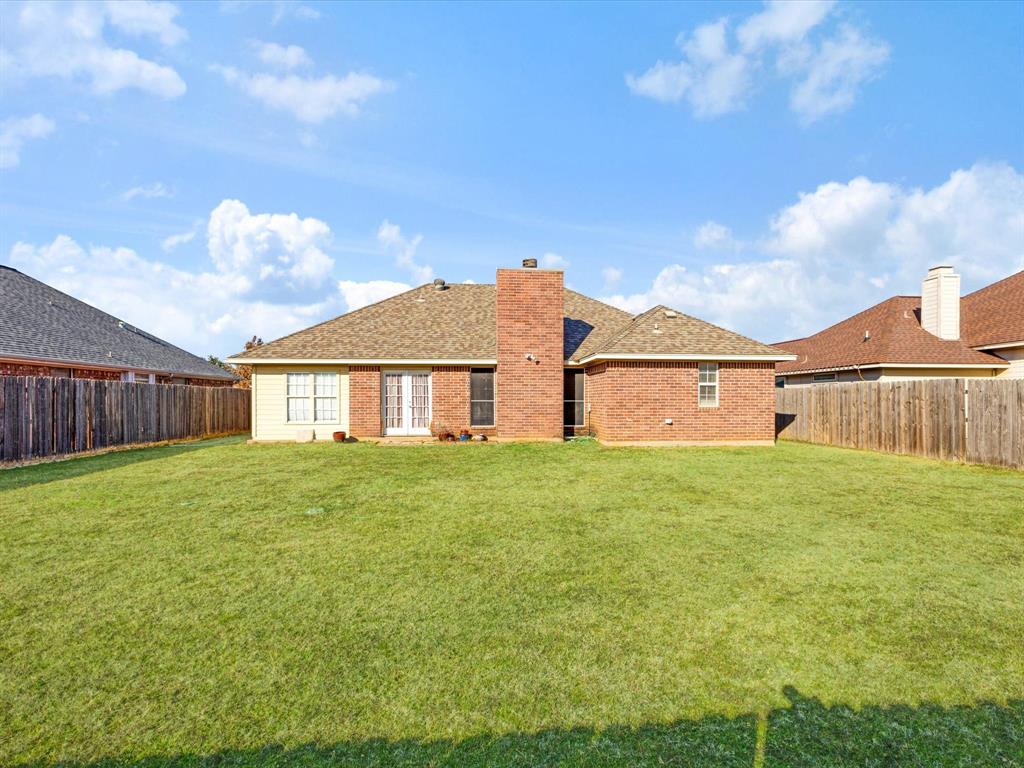 207 Quail Run Aubrey, TX 76227 - Photo 22 of 30 Back of house featuring a fenced backyard, brick siding, a chimney, and a shingled roof