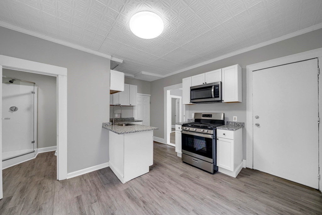 49 6th Street Lowell, MA 01850 - Photo 12 of 37 a kitchen with granite countertop a stove and a refrigerator